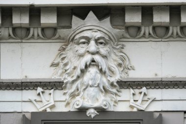 An old stone building with a marble facade showing the face of the Roman god Neptune, the god of the sea.