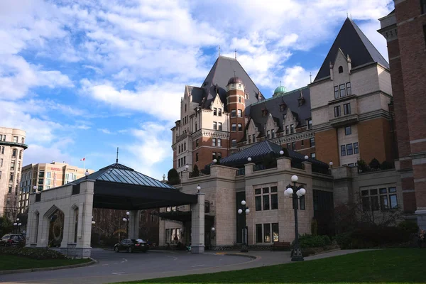 The front entrance to the landmark Empress hotel in downtown Victoria, BC with a blue sky background and white clouds.