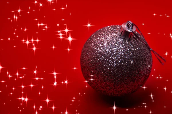 Ασημένια Χριστουγεννιάτικη Μπάλα Κόκκινο Φόντο Που Περιβάλλεται Από Λαμπερά Αστέρια — Φωτογραφία Αρχείου