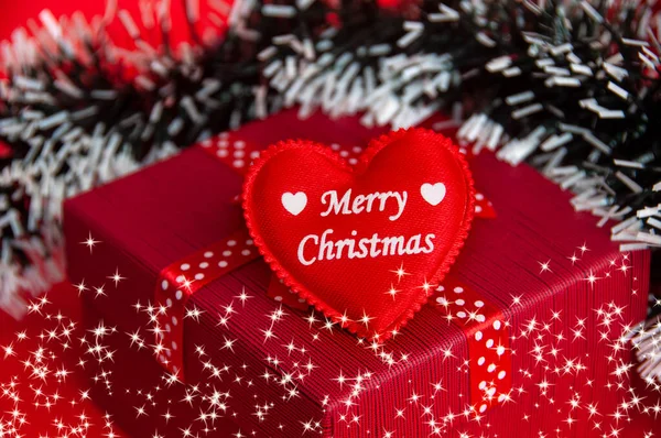 stock image Merry Christmas text on heart shape on top of red color present with Christmas decoration background. Christmas gift and celebration concept.