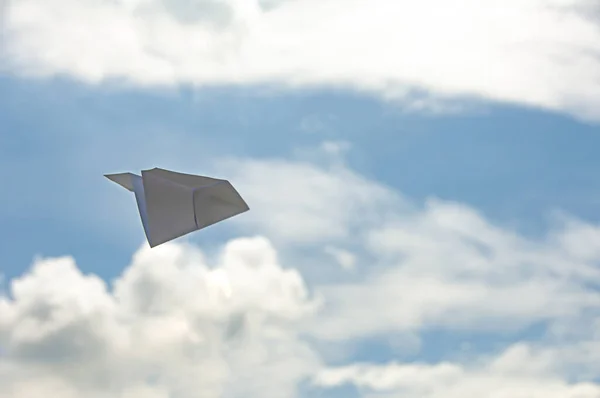 stock image Flying white paper plane on blue sky background.