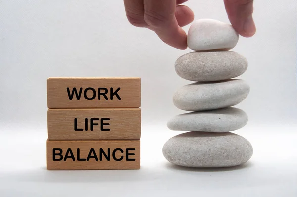 Work life balance text on wooden blocks with hand stacking zen stones. Working culture concept.