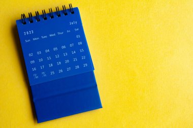 Sarı kapaklı mavi takvime göre Temmuz 2023.