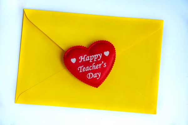 Happy teacher's day text on heart shape with yellow envelop background.