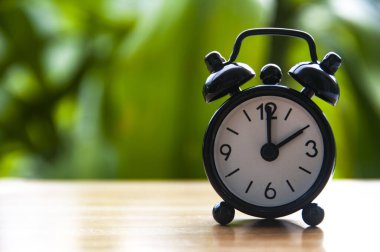 Alarm clock pointing at 2pm with blurred nature background. With customizable space for text. Copy space.