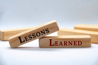 Lessons learned text on wooden blocks on white cover background.