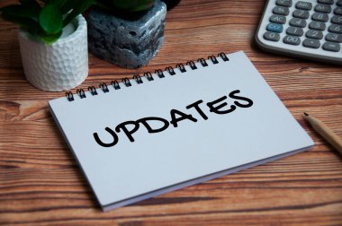 Updates text on notebook with green plant and calculator background. Business concept.