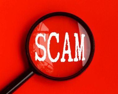 Scam text on red cover with magnifying glass. Scamming and fraud concept.