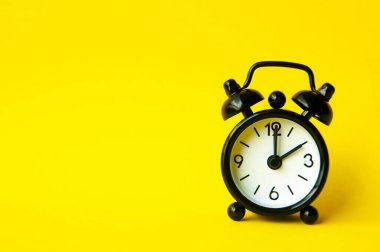 Alarm clock pointing at 2 am or pm with customizable space for text or ideas. Copy space with yellow background.