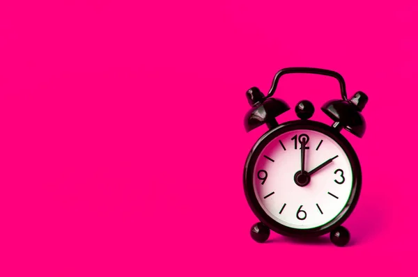 Alarm clock pointing at 2 am or pm with customizable space for text or ideas. Copy space with pink background.