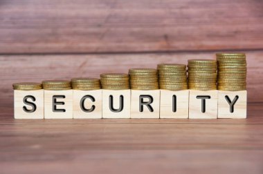 SECURITY text engraved on wooden blocks with gold coins on wooden background. Security and protection concept.