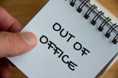 Ofis dışı bilgilendirme metninin beyaz not defterindeki üst görünümü. İş konsepti.