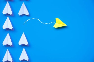 Sarı kağıttan uçak origamisi diğer beyaz uçakları mavi zemin üzerinde bırakır metin ya da fikirler için özelleştirilebilir alanla. Liderlik becerileri kavramı ve kopyalama alanı.