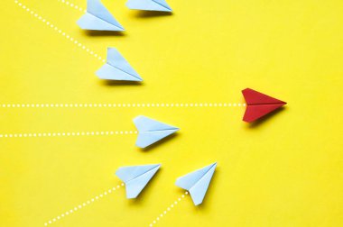 Beyaz kağıt uçaklar origami 'nin sarı zemin üzerinde kırmızı uçağı takip edişinin üst görüntüsü metin ya da fikirler için özelleştirilebilir alan. Liderlik becerileri kavramı ve kopyalama alanı.