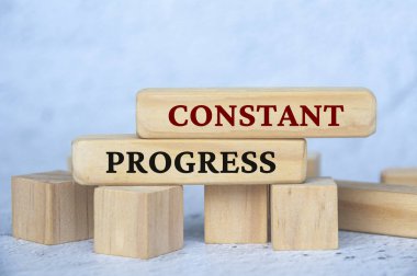 Constant progress text on wooden blocks with blur cover background. Business culture and Operational excellence concept. clipart