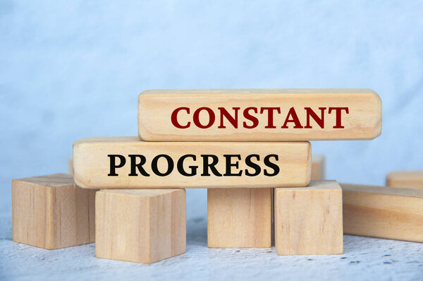 Constant progress text on wooden blocks with blur cover background. Business culture and Operational excellence concept.