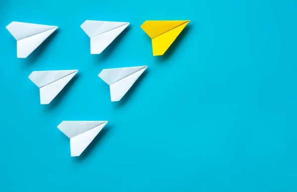 Top view of paper airplane - Yellow paper airplane origami leading other white airplane on blue background. Leadership concept