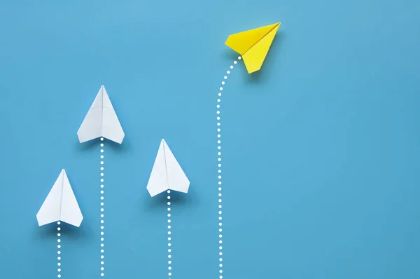 stock image Top view of yellow paper airplane origami flying to a different direction separate from other white airplanes on blue background. Leadership and business concept.