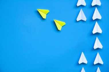 İki sarı kağıttan uçak origamisi diğer beyaz uçakları mavi zemin üzerinde bırakır metin veya fikirler için özelleştirilebilir alan ile. Liderlik becerileri kavramı.