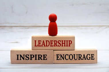 Leadership, Inspire and Encourage text on wooden blocks with red figure on top. Leadership concept clipart