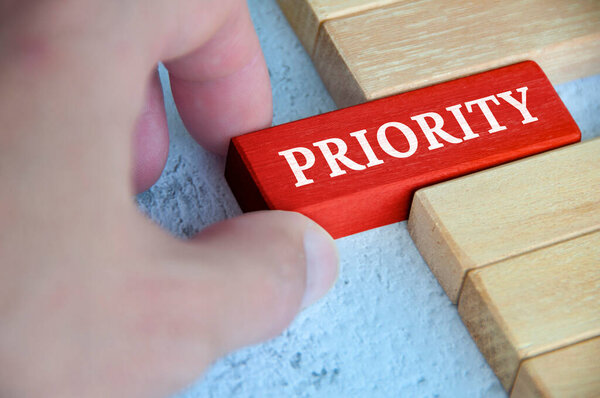 Ручное размещение красных деревянных блоков с текстом - приоритет. Приоритет и концепция бизнеса.