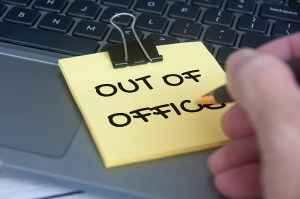Out of office notification text sticky notes with laptop background. Out of Office concept.