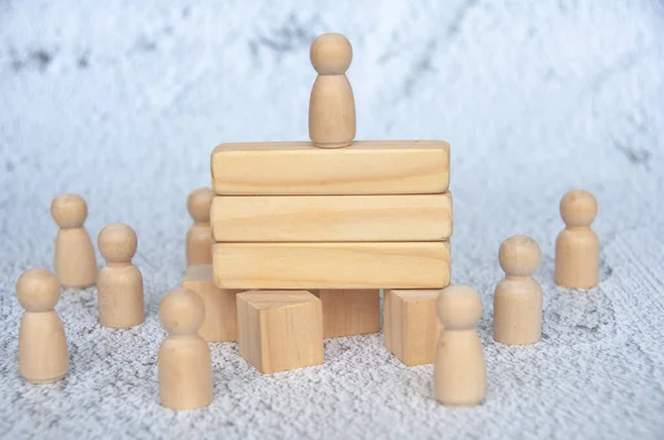 Wooden figure on top of wooden blocks with customizable space for text. Copy space and leadership concept.