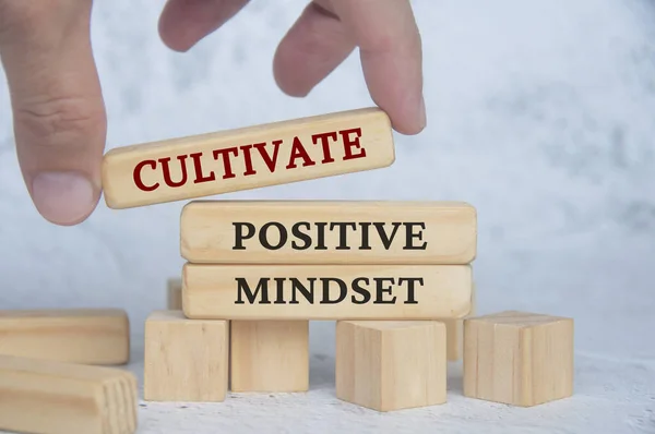 Cultivate positive mindset text on wooden blocks. Continuous improvement concept.