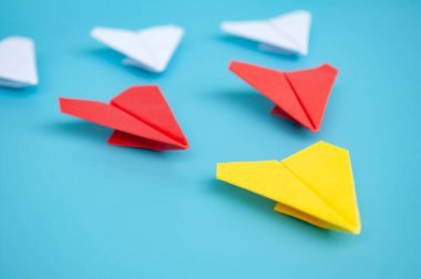 Sarı kağıttan uçak origamisi mavi arka planda diğer kağıt uçaklara öncülük ediyor. Liderlik kavramı.