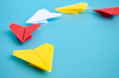 Sarı kağıttan uçak origamisi mavi arka planda diğer kağıt uçaklara öncülük ediyor. Liderlik kavramı.
