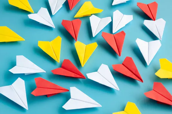 Yellow paper plane origami leading other white paper planes on blue background. Leadership concept.