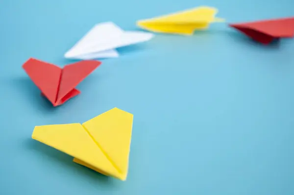 Yellow paper plane origami leading other paper planes on blue background. Leadership concept.