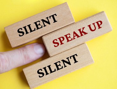 Tahta bloğu işaret eden parmaklar sarı kapaklı arka planda konuşuluyor. Konsepti dile getirmek için cesaret.