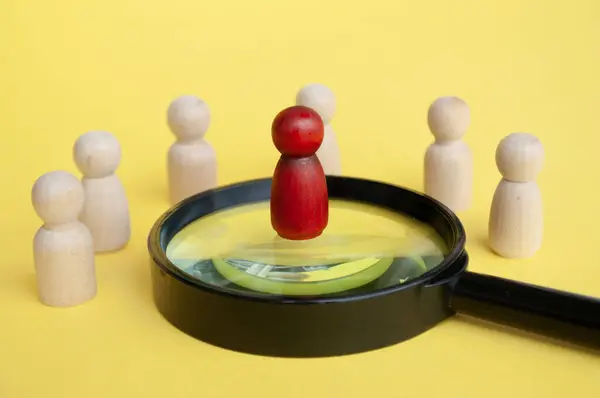 Leadership concept, red figure standing on magnifying glass leading the rest of figures on yellow cover background