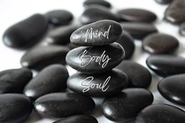Mind, Body and soul text engraved on black zen stones.