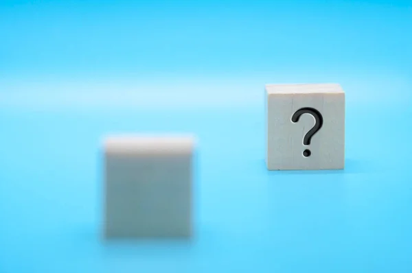 Question mark on wooden block with blue background. Question and answer session