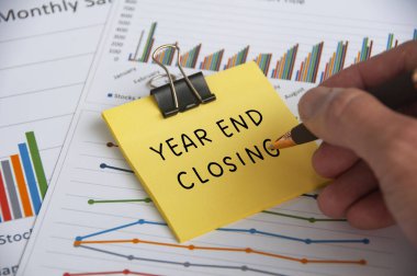 İstatistik ve grafik arkaplanlı yapışkan notta el yazısı Yılı sonu metni kapanıyor.