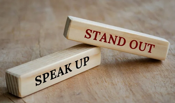Stand out and speak up text on wooden blocks. Business concept.