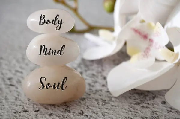 Body, Mind and Soul text engraved on white zen stones Meditation and spa concept.