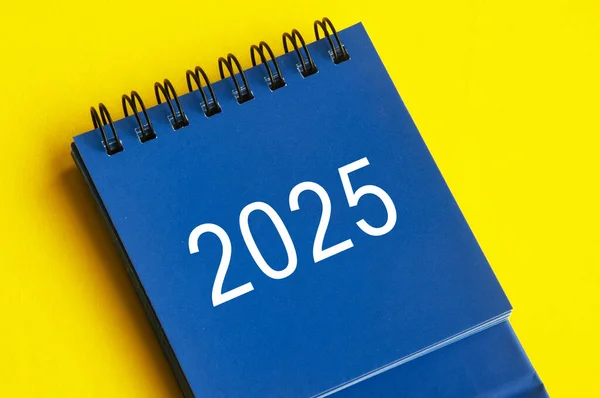 2025 blue desk calendar on yellow cover background. Calendar concept.