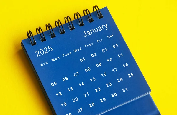 January 2025 blue desk calendar on yellow cover background. Calendar concept.