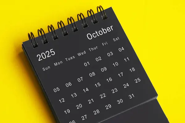 stock image October 2025 black and white desk calendar on yellow cover background. Calendar concept.