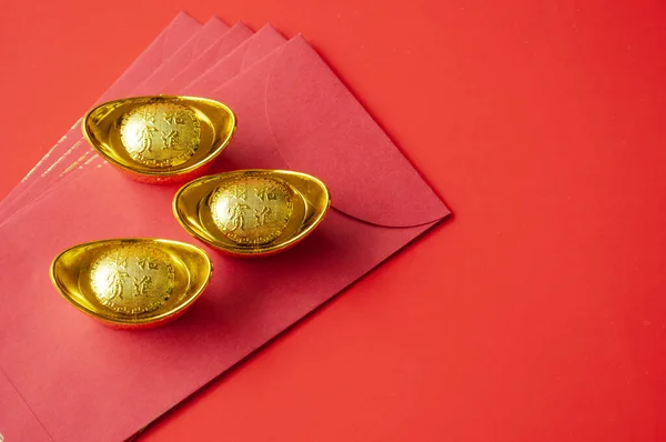 Golden ingot on top of red packets. Chinese New Year celebration concept.
