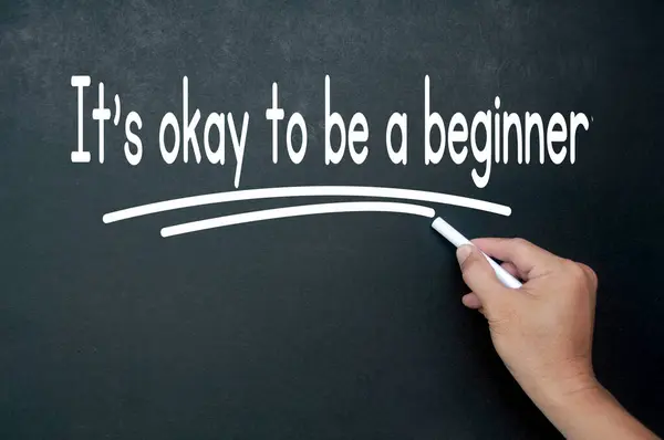 Hand writing It is okay to be a beginner affirmation on black board. Affirmation concept.