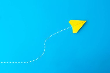 Mavi arkaplanda çizgi noktaları olan sarı kağıt uçak manzarası.