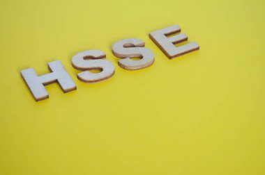 Sarı arka planda Sağlık, Güvenlik, Güvenlik ve Çevreyi temsil eden HSSE ahşap harfleri.