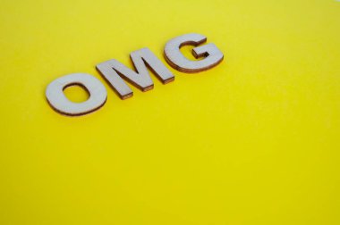 OMG wooden letters representing Oh My God on yellow background. clipart
