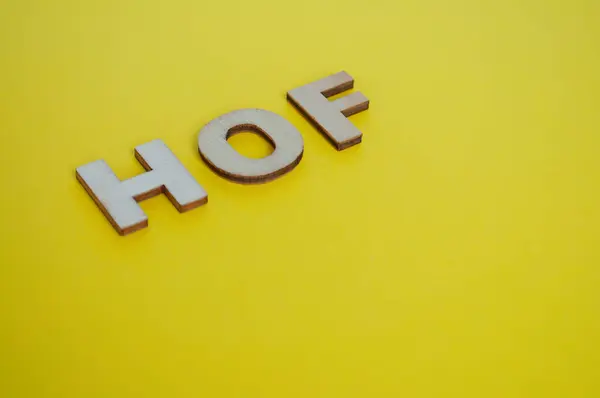 HOF wooden letters on yellow cover background. Senior Executive Level concept.