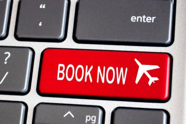 Book now text on red keyboard. Traveling concept. clipart