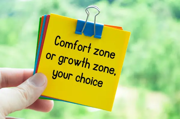 Hand holding yellow note pad with text about Comfort zone and growth.